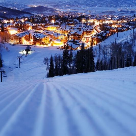 Skiing pathway with the illuminated city view near Chateaux Deer Valley