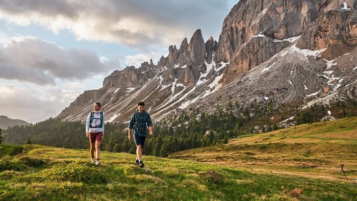 Two hikers walking towards mountains near Falkensteiner Hotel Kronplatz