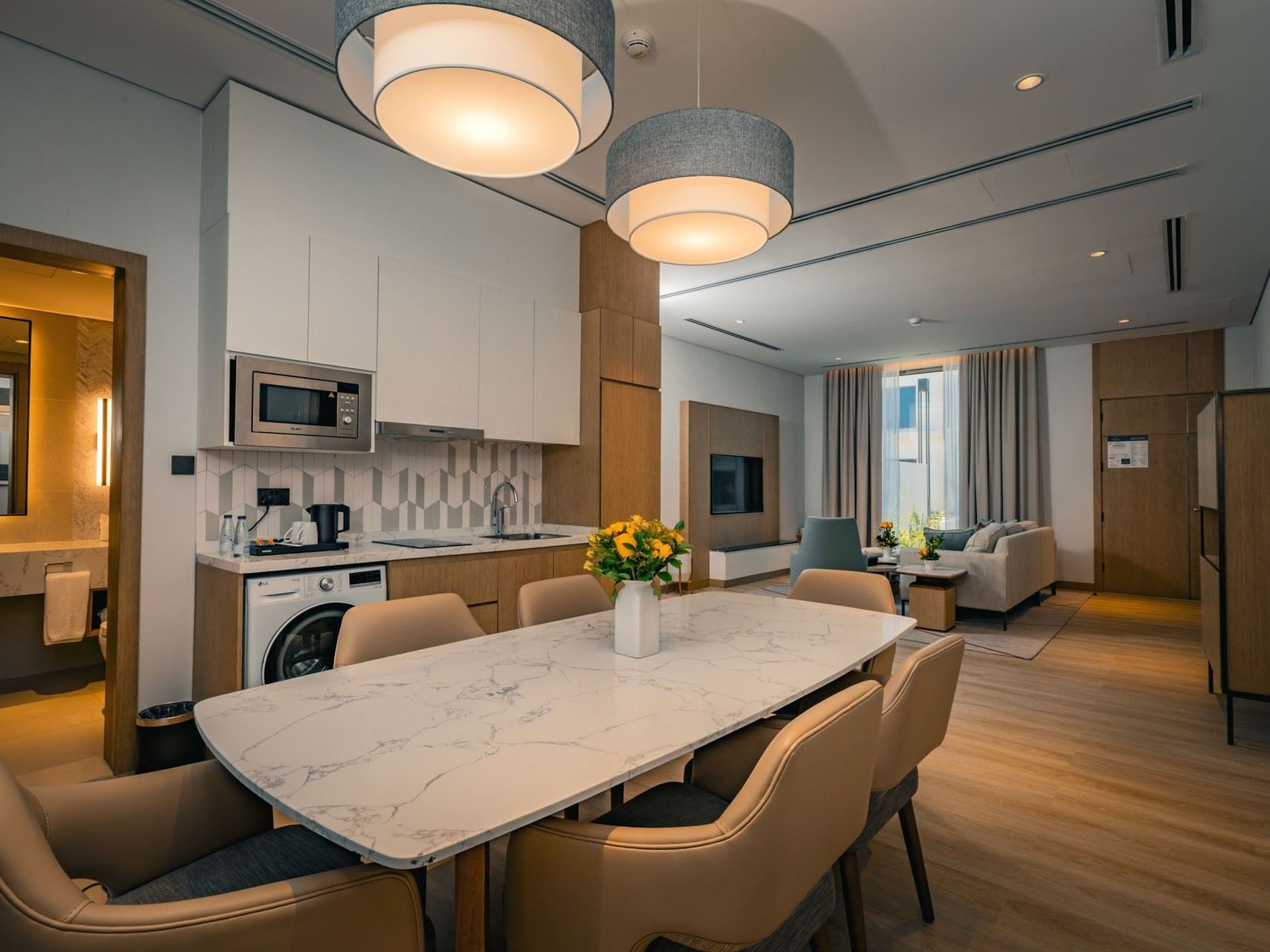 Modern open-plan living space with dining table, kitchen, and living area with couch and TV.