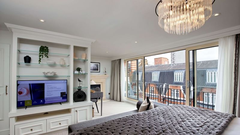 Three Bedroom Penthouse suite with large bed, TV, and Juliette balcony at The Capital Hotel, Apartments & Townhouse in London.