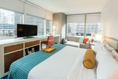 Bed, sofa & a TV in Deluxe King Corner Room at Kinzie Hotel