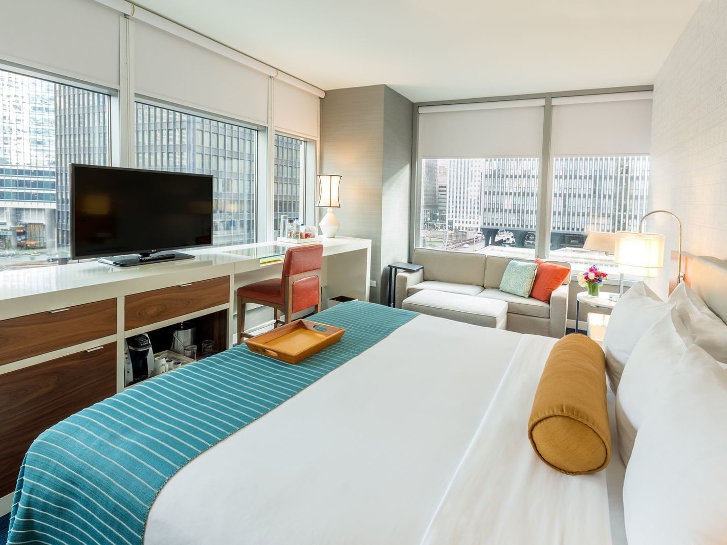 Bed, sofa & a TV in Deluxe King Corner Room at Kinzie Hotel