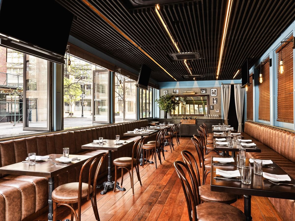 The Parlor at Estelle's features brown leather banquettes, dark wood tables, and a striking black slatted ceiling at Gansevoort Meatpacking NYC.