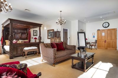 Red sofa in a room with a king bed at Orsett Hall Hotel