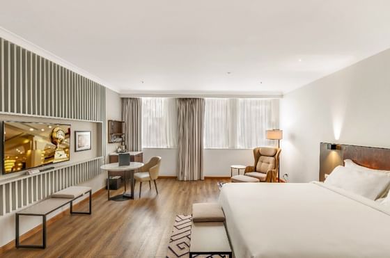 TV, lounge & king bed with a wooden floor in a Room at Federal Hotels International