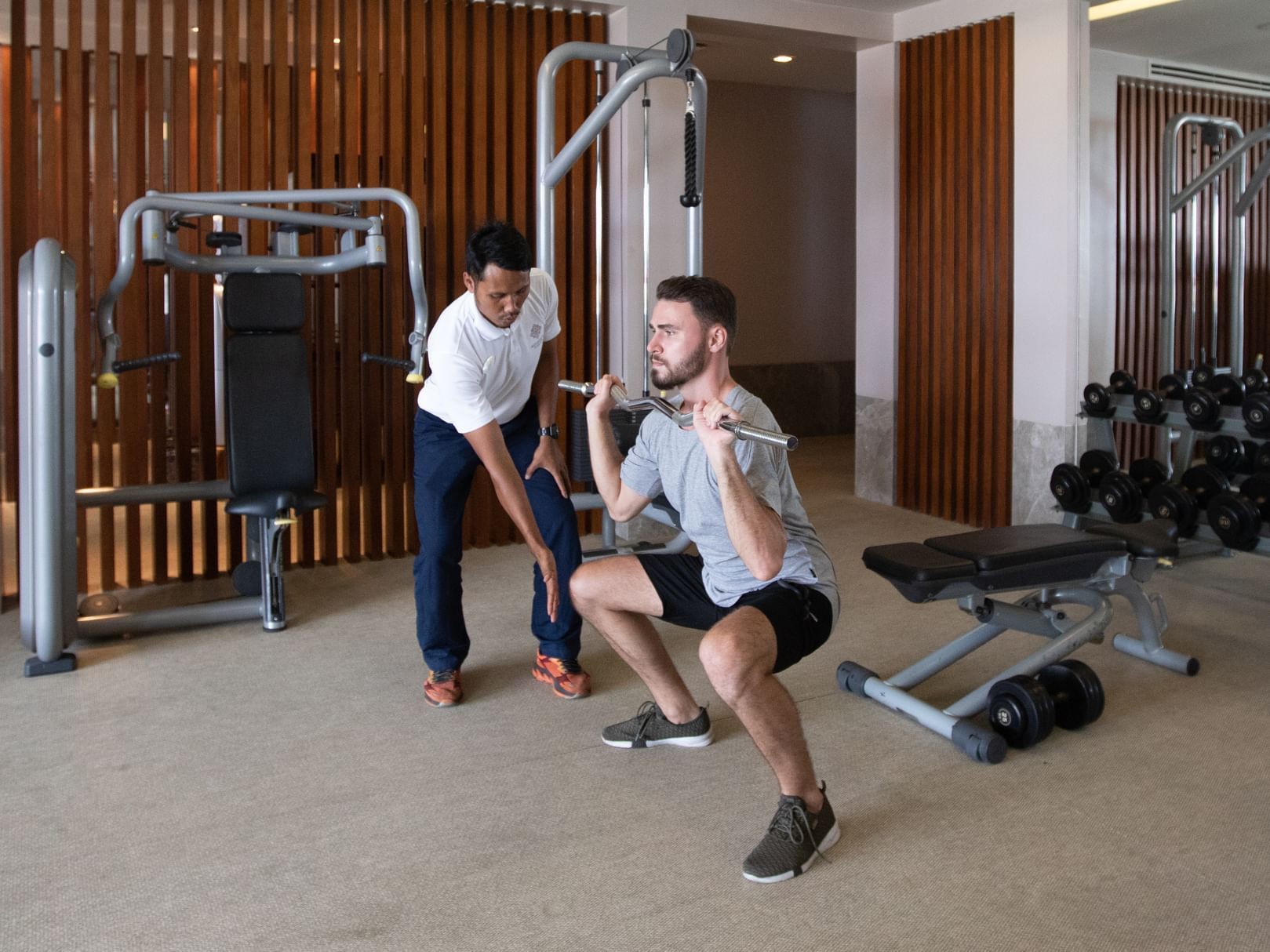 a male guest working out in the gym with a fitness instructor