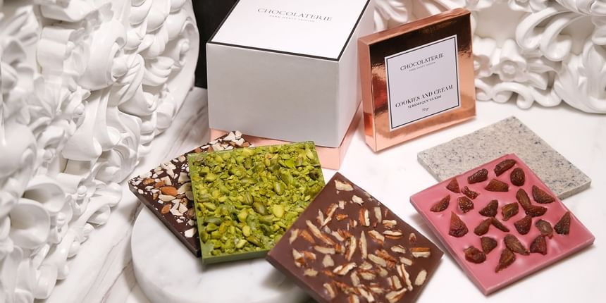 Assorted gourmet chocolate bars with dried fruits and nuts on a marble surface in Chocolaterie at Park Hyatt Saigon