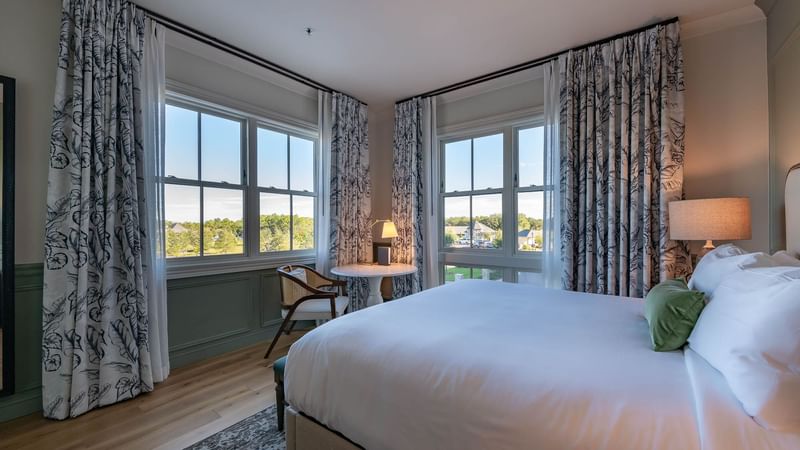 Work desk & King bed by the window with a golf ground view in King Room at Camp Creek Inn