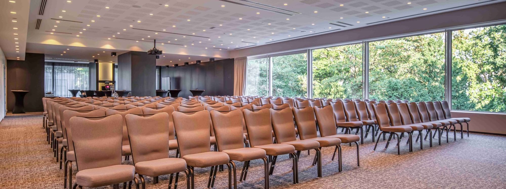 Park Ballroom with rows of beige chairs and patterned carpet at The Hotel Brussels