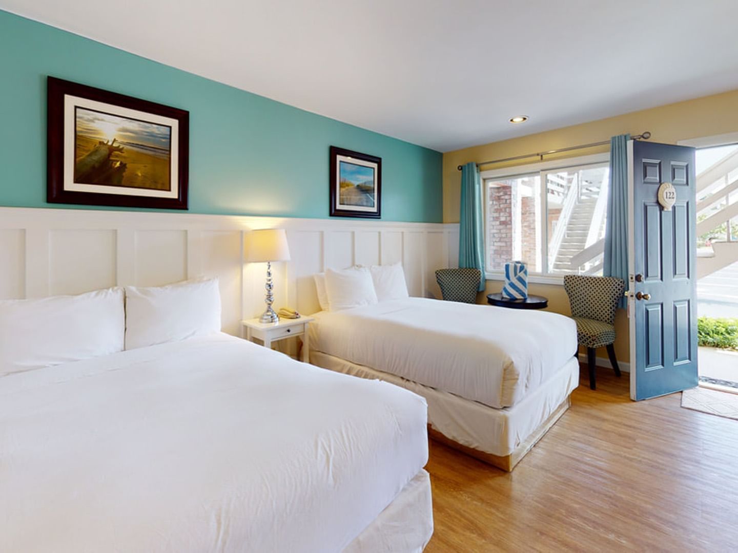 Two beds with table lamp by the open door and seating in Two Double at Breezeway Boutique Hotel