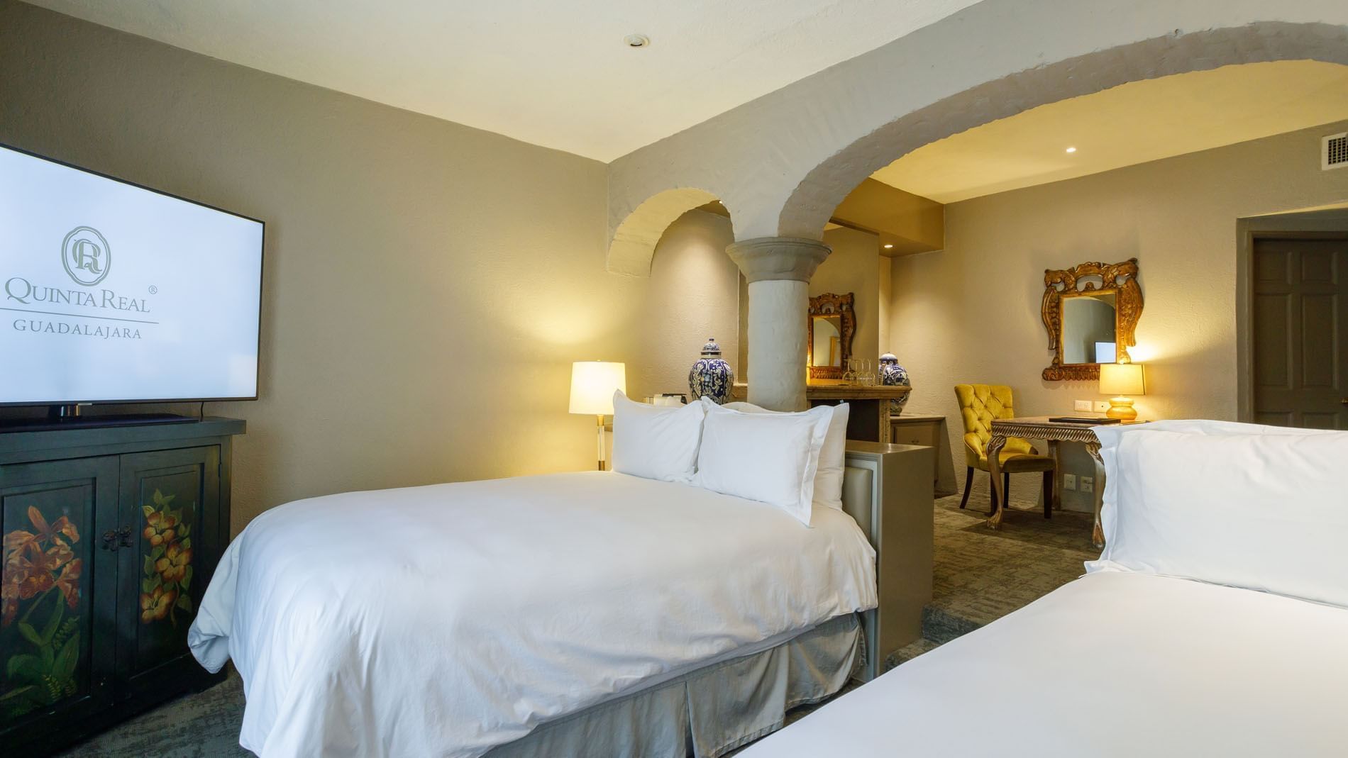 2 Double Master Suite, beds framed by classic stone pillars and a gold-framed mirror, at the Quinta Real Guadalajara hotel