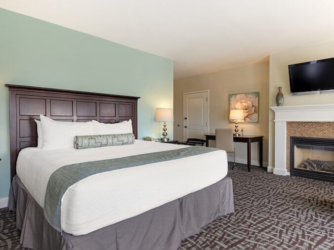 TV, nightstands & seating area by the bed in Meetinghouse King Deluxe Ocean View Room at Union Bluff Hotel