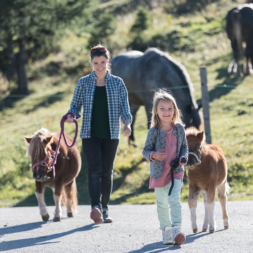 Mother & kid walking with small ponies at Ponyalm horse center near Falkensteiner Hotel Cristallo