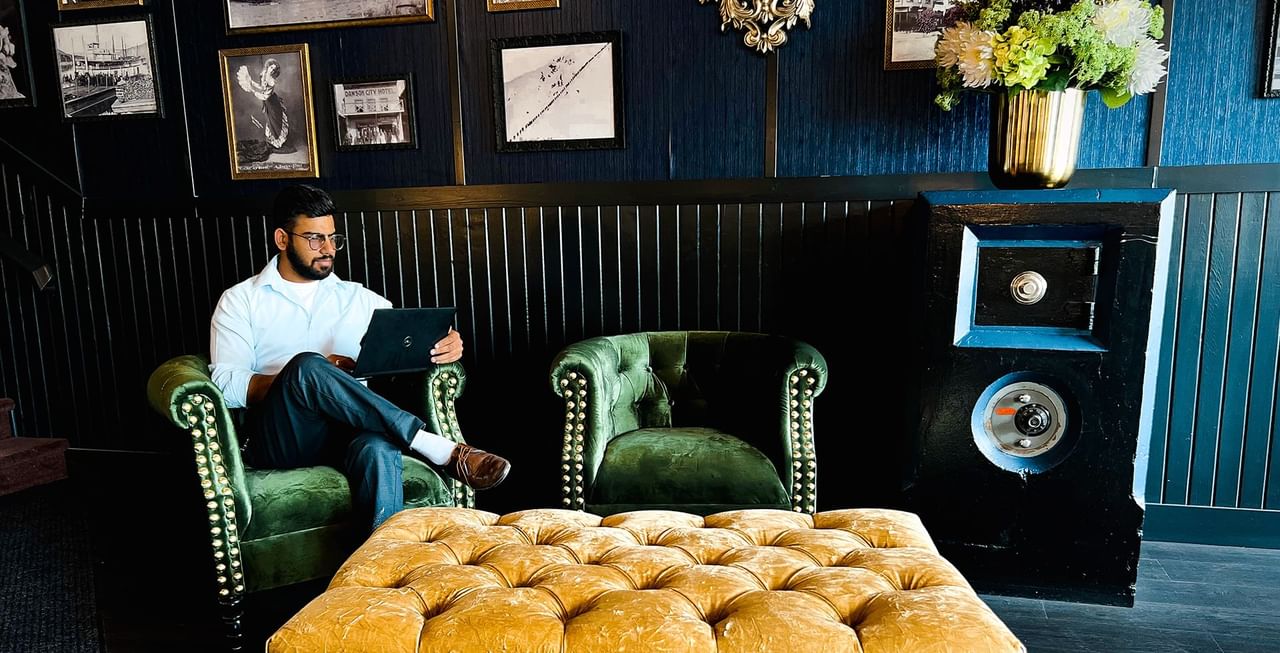 A person sitting on a couch in the lobby of Midnight Sun, a Coast Hotel