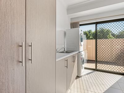 Clean laundry room with washing machine, cabinets, and sliding glass door at La Trobe University Regional Housing – Mildura.