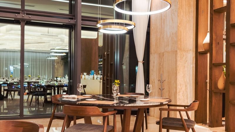 Upscale circular dining table in La Huerta featuring marble top, modern lighting, and wood accents at Camino Real Merida