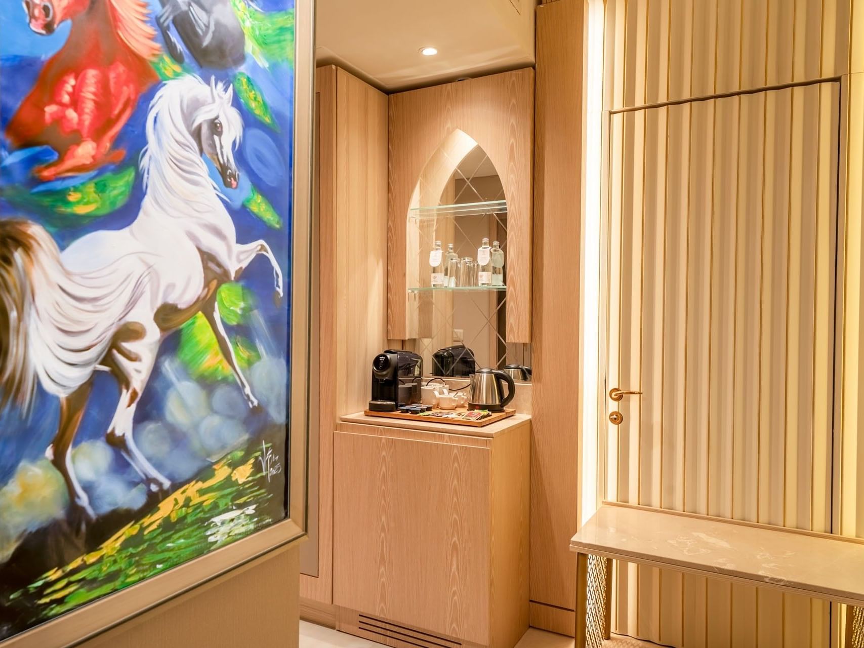 A wooden cabinet with coffee machines and a horse painting at World Heart Hotel Baghdad.
