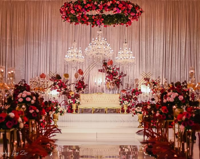 Opulent wedding stage with chandeliers, red flowers, and candles at Sofitel Brisbane Central