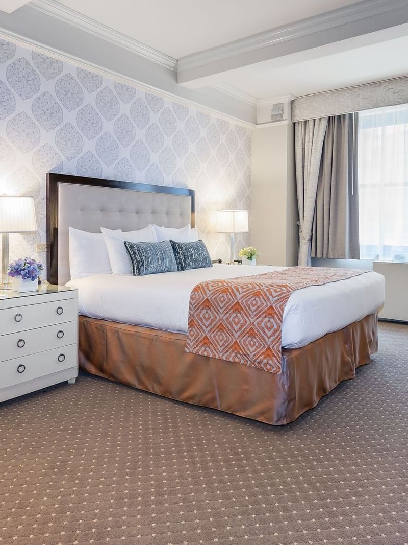 King bed & bedside lamp with patterned wallpaper and large window in Premier City View at Warwick New York
