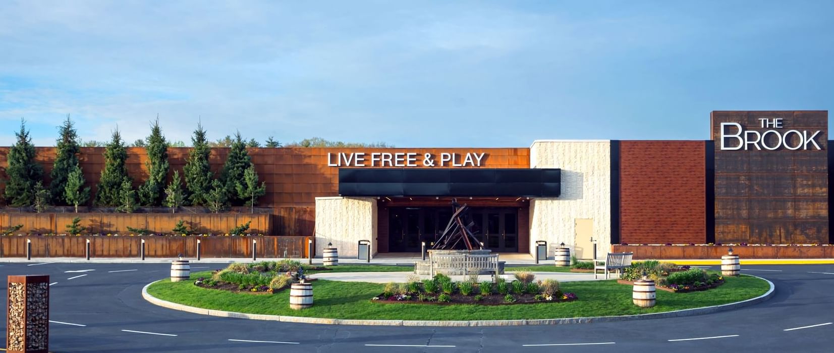 Exterior view of modern gaming building with Live Free and Play sign at driveway entrance venue at The Brook