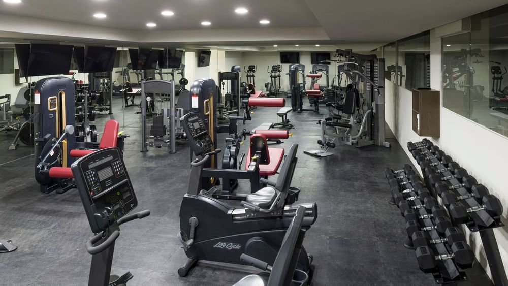 Fully equipped fitness center with stationary bikes, weight machines, and dumbbells at Real Inn Celaya