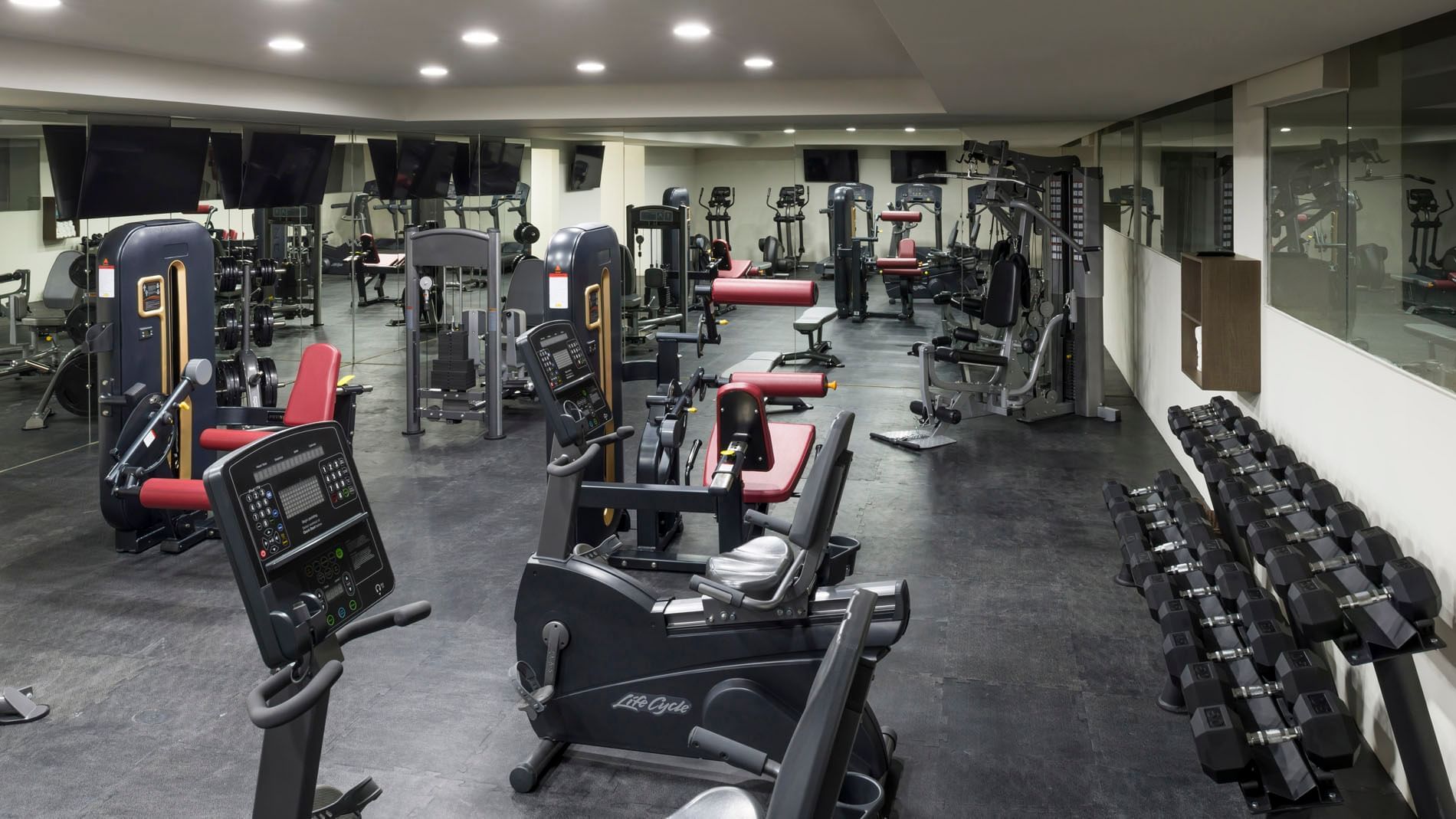Fully equipped fitness center with stationary bikes, weight machines, and dumbbells at Real Inn Celaya