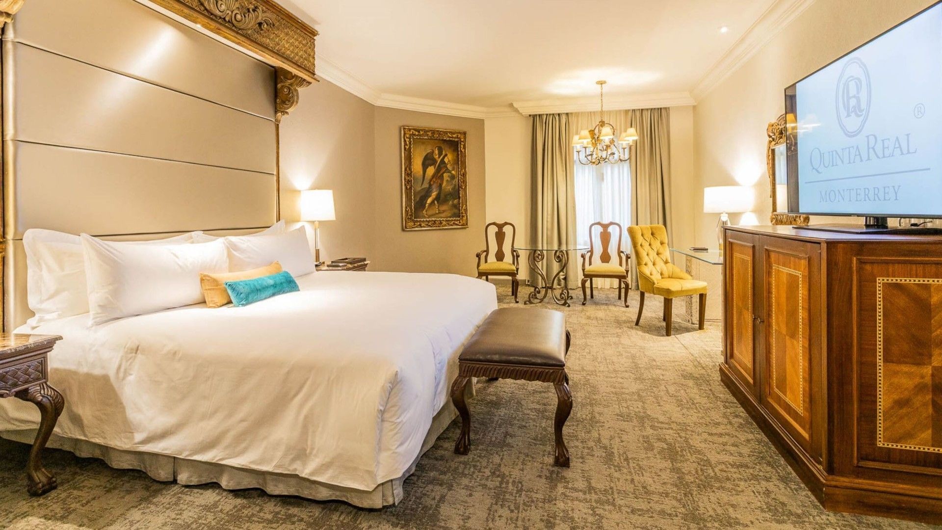 Elegant King Master Suite with a classic wood bench, yellow armchair, and gold accents at Quinta Real Monterrey