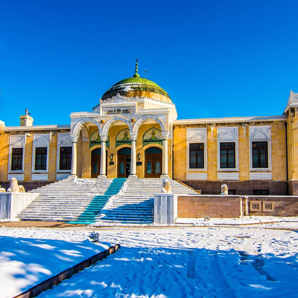 The Ethnography Museum of Ankara with snow-covered ground and a flag on a clear day.