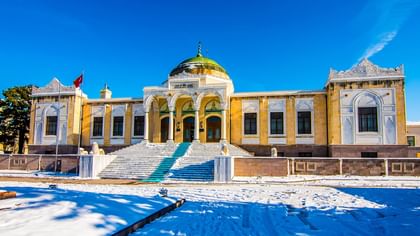 The Ethnography Museum of Ankara with snow-covered ground and a flag on a clear day.