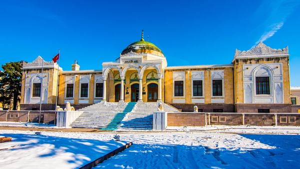 The Ethnography Museum of Ankara with snow-covered ground and a flag on a clear day.