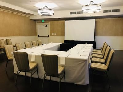 A u-shaped boardroom & white screen at Horton Grand Hotel