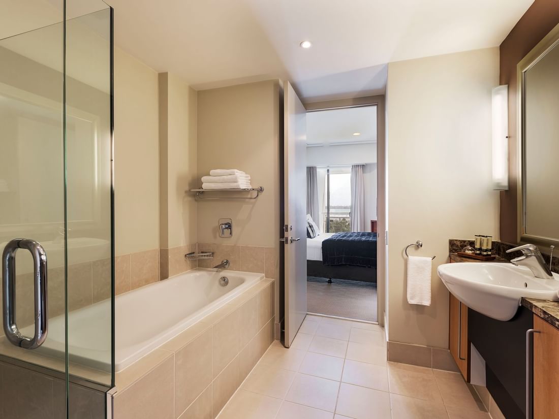 Marina View One Bedroom Suite bathroom with vanity and bathtub by the open door at the Sebel Auckland Viaduct Harbour