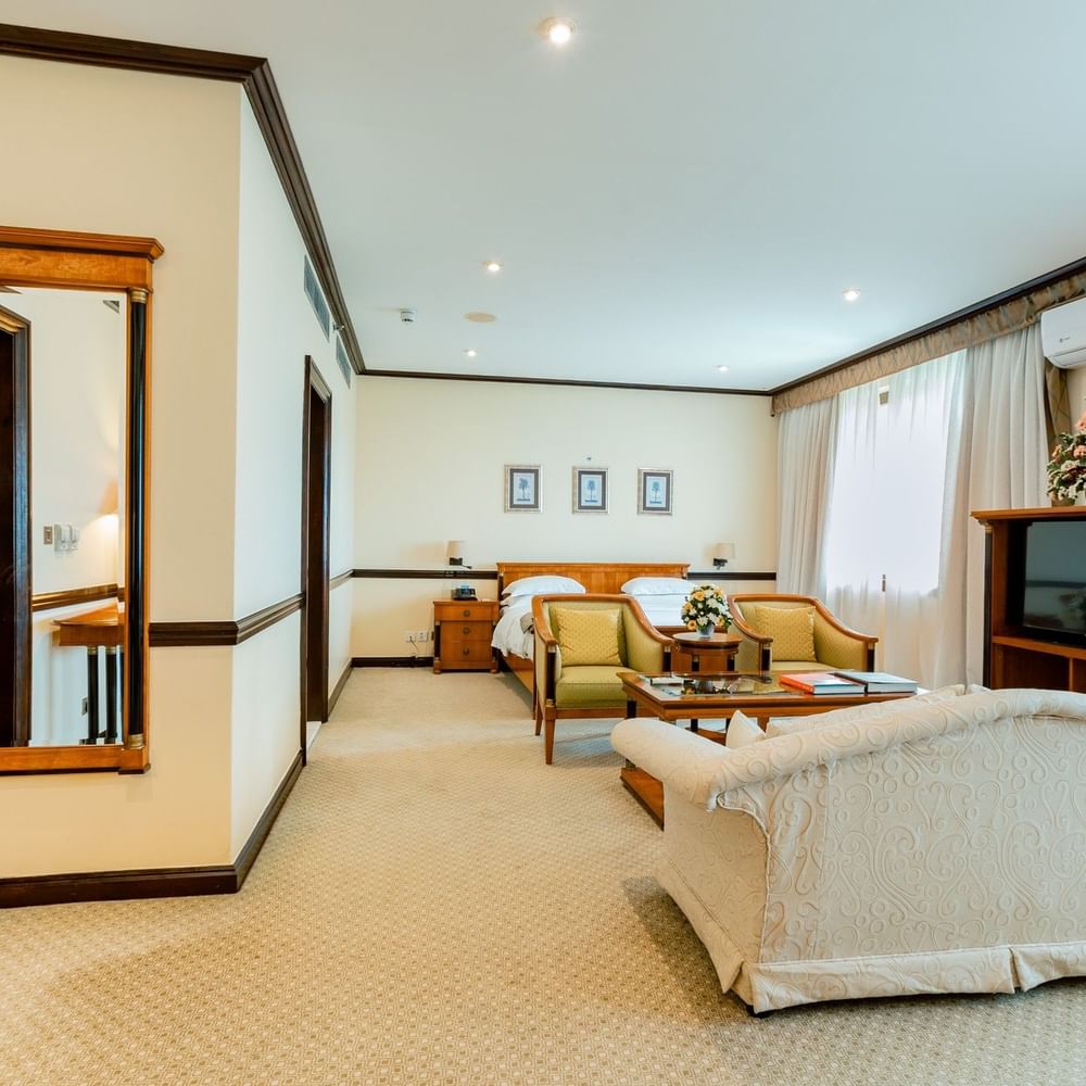 Elegant room with a bed, armchair, and TV at Dar Es Salaam Serena Hotel in Dar es Salaam.