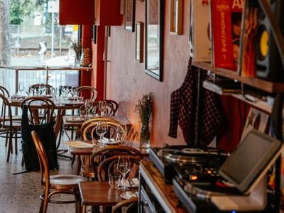 Empty cosy restaurant with wooden tables and chairs, and DJ setup near Swift Walk.