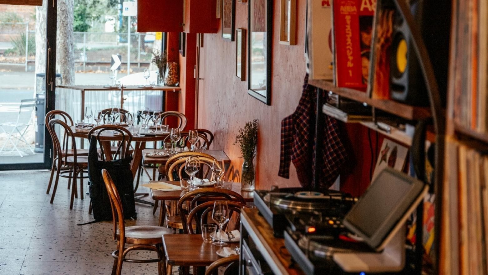 Empty cosy restaurant with wooden tables and chairs, and DJ setup near Swift Walk.