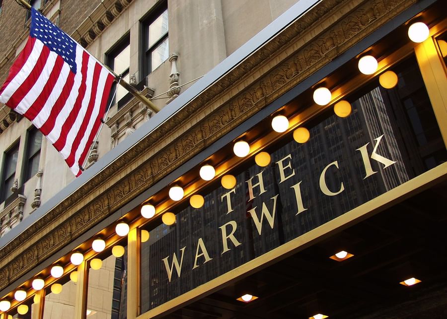 The Warwick hotel entrance with American flag and illuminated sign at Warwick New York.