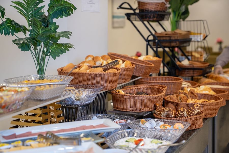 Selection of fresh bread rolls and pastries displayed in wicker baskets at Saja by Warwick Makkah