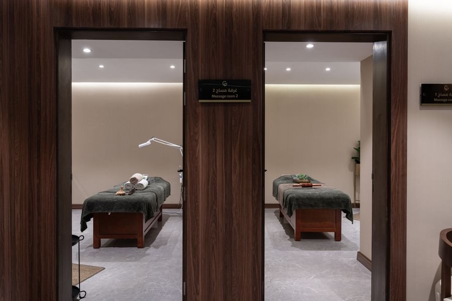 Massage tables in private Golden Time Spa rooms framed by wood-paneled doorways under bright lights at Warwick Al Taif Hotel