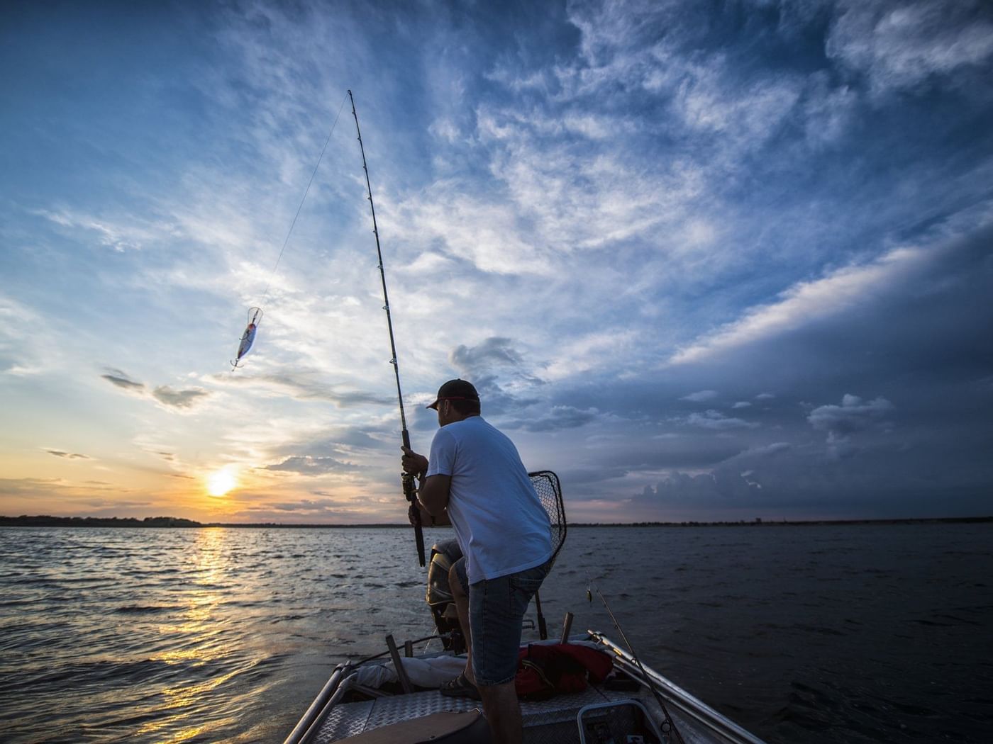 A man fishing on a calm lake during the sunset near Grand Fiesta Americana