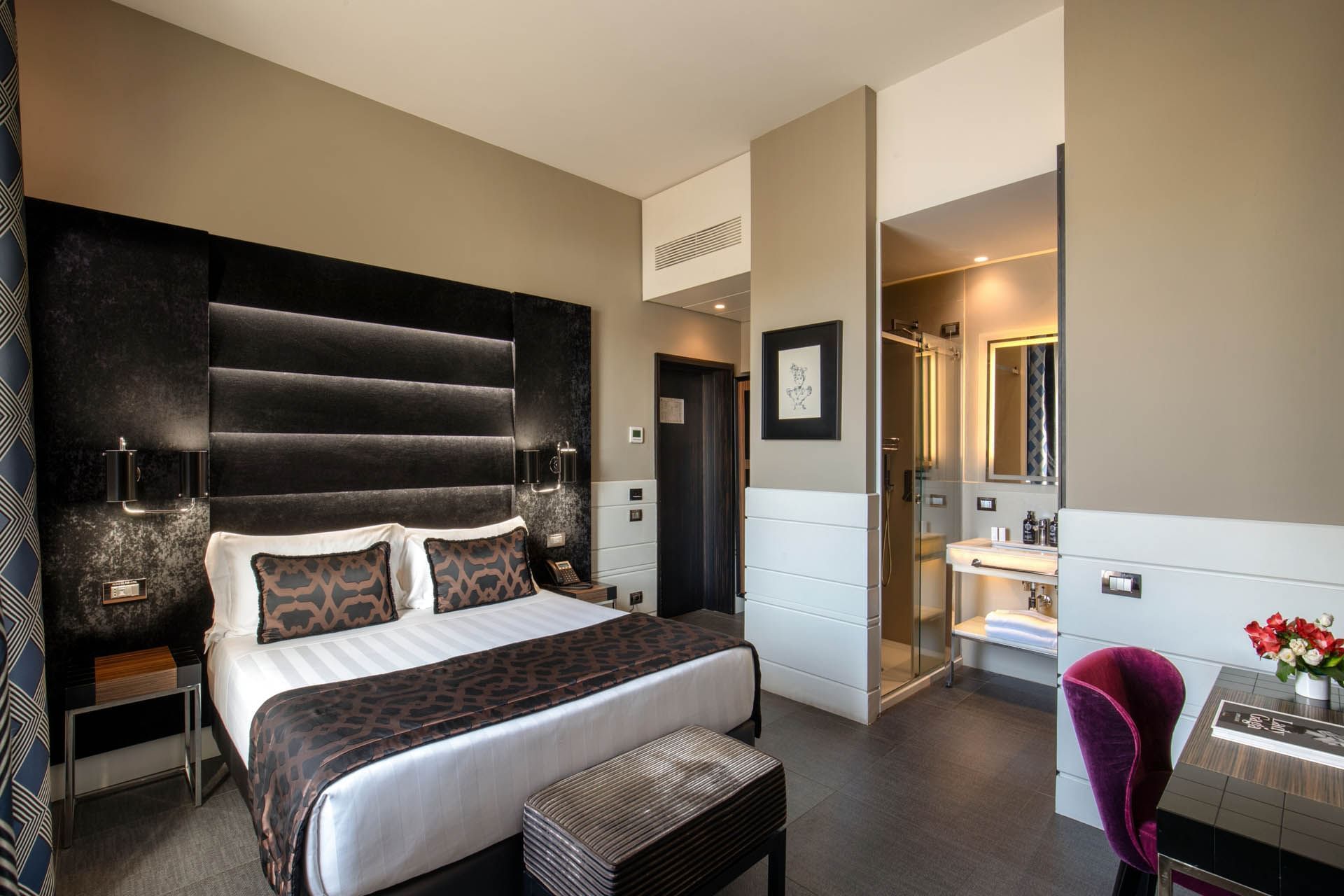 Work desk facing bed with side tables and attached bathroom in Classic Room at The Glam Hotel