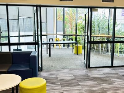 Lounge area with couches, tables, and yellow stools at UniLodge Auckland City.