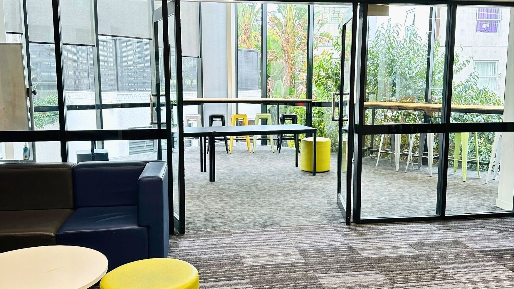 Lounge area with couches, tables, and yellow stools at UniLodge Auckland City.