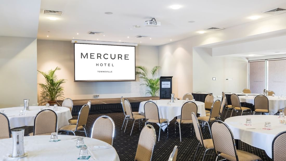 Interior of Crystal Room featuring cabaret table setup and a screen at Mercure Hotel Townsville