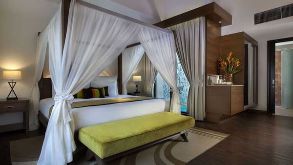 Spacious Lake Villa bedroom, lime green bench, and dark wood floors at The Banjaran Hotsprings Retreat