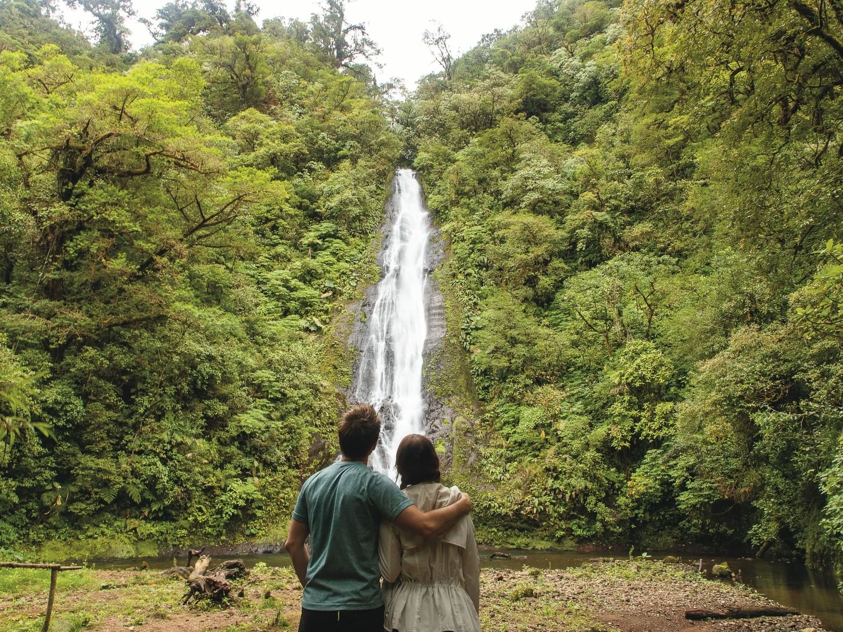 couple standing in front of watefall