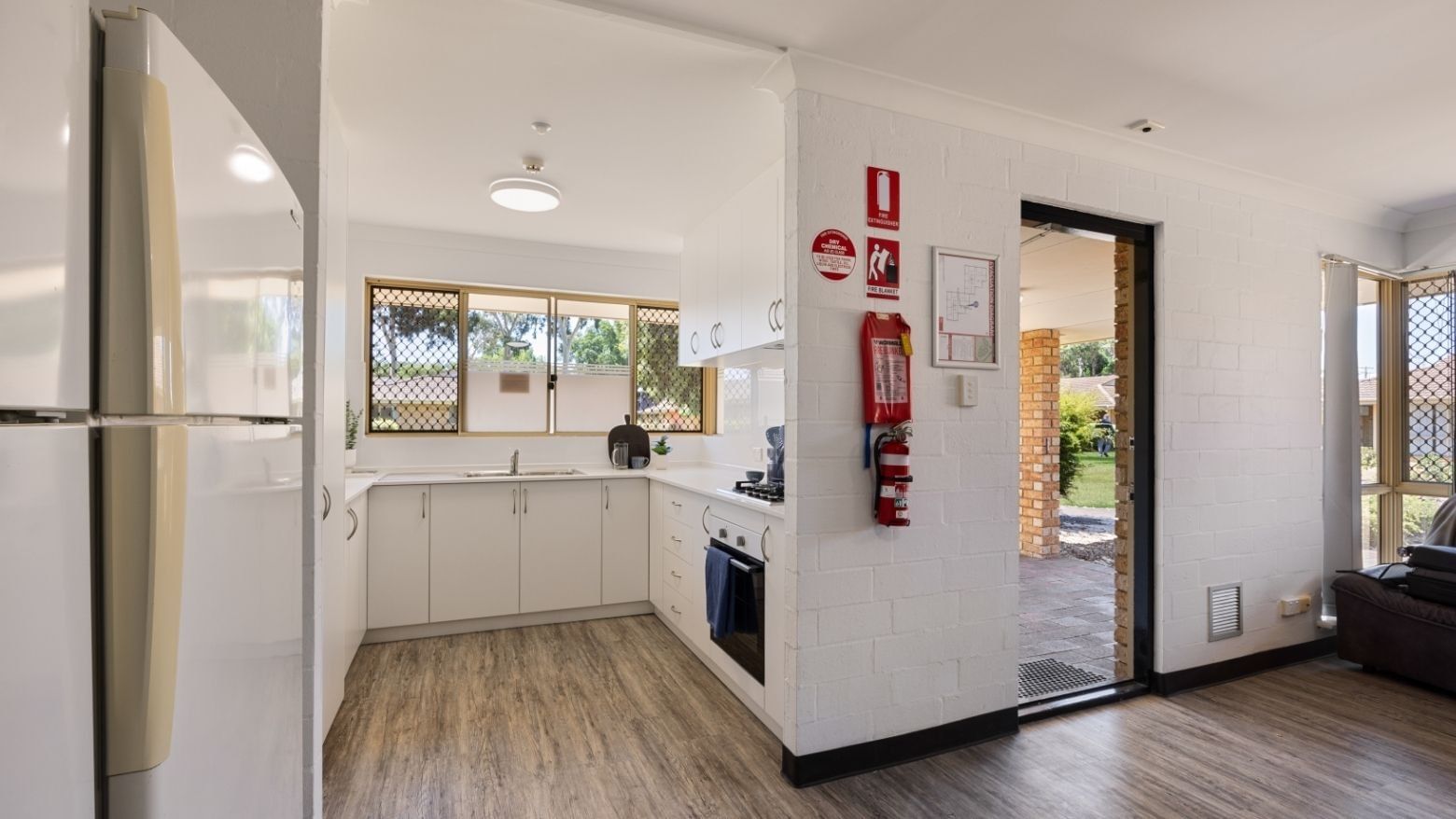 Modern kitchen with white cabinets, appliances, and wooden floor at UniLodge Vickery House.