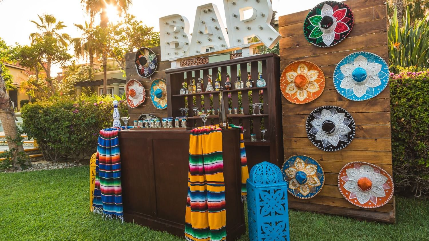 Palapa Fiesta Mexican Dinner bar with colorful sombreros and blankets, set up on a grassy lawn at Hacienda del Mar Los Cabos