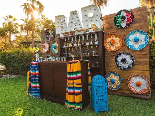 Palapa Fiesta Mexican Dinner bar with colorful sombreros and blankets, set up on a grassy lawn at Hacienda del Mar Los Cabos