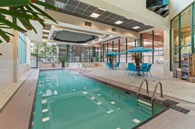Indoor pool with seating under blue umbrellas at Rosedale on Robson Suite Hotel, one of the luxury hotels in Vancouver, BC