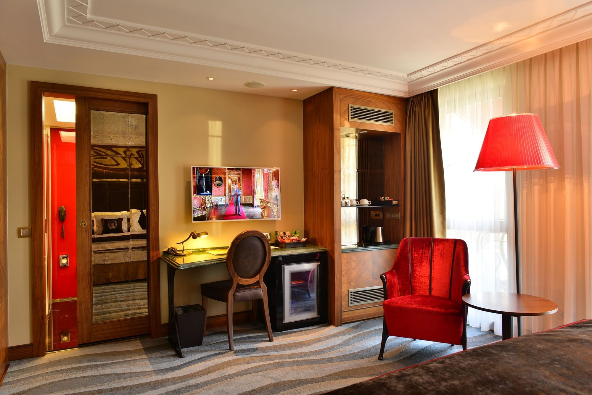 Red velvet armchairs by a round table under soft light in deluxe room at Warwick Ankara